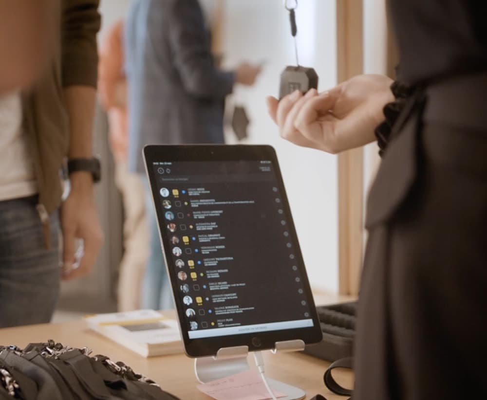A tablet on the welcome desk shows the list of attendees while badges are handed out